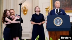 Alsu Kurmasheva's family hugs as President Joe Biden speaks about the release of Russian detainees Paul Whelan, Evan Gershkovich, Kurmasheva and Vladimir Kara-Murza at the White House, Aug. 1, 2024. At center is Paul Whelan's sister, Elizabeth Whelan.