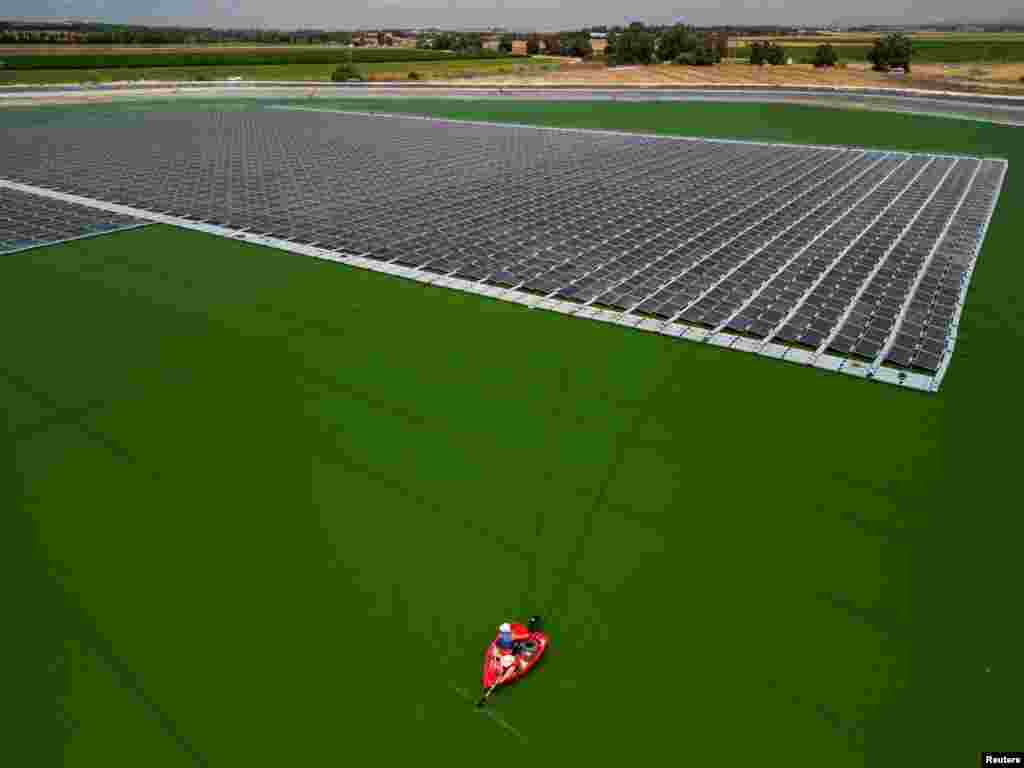 An aerial view shows workers from Nofar Energy installing solar panels on a water reservoir outside of Kibbutz Or HaNer, Israel, June 19, 2023.