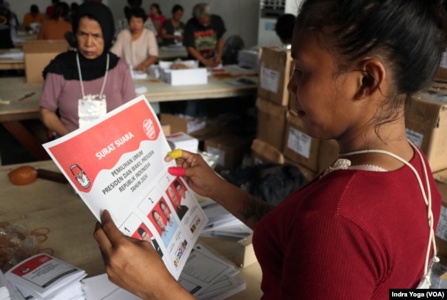 Seorang relawan memeriksa lembar surat suara untuk pemilihan calon presiden dan wakil presiden di Gudang KPU Kotamadya Jakarta Timur, Kamis, 11 Januari 2024. (Foto: Indra Yoga/VOA)