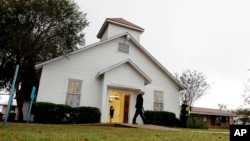 FILE - In this Nov. 12, 2017, file photo, a man walks out of the memorial for the victims of a shooting at Sutherland Springs First Baptist Church in Sutherland Springs, Texas.