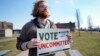 Eric Suter-Bull holds a Vote Uncommitted sign outside a voting location at Saline Intermediate School for the Michigan primary election in Dearborn, Michigan, Feb. 27, 2024. 