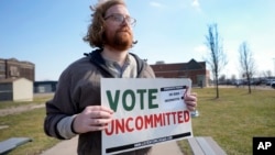 Eric Suter-Bull holds a Vote Uncommitted sign outside a voting location at Saline Intermediate School for the Michigan primary election in Dearborn, Michigan, Feb. 27, 2024. 