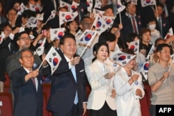 South Korea's President Yoon Suk Yeol and his wife, Kim Keon Hee, wave flags of South Korea during a ceremony held to celebrate the 79th Korean National Liberation Day at the Sejong Center of the Performing Arts in Seoul, Aug. 15, 2024.