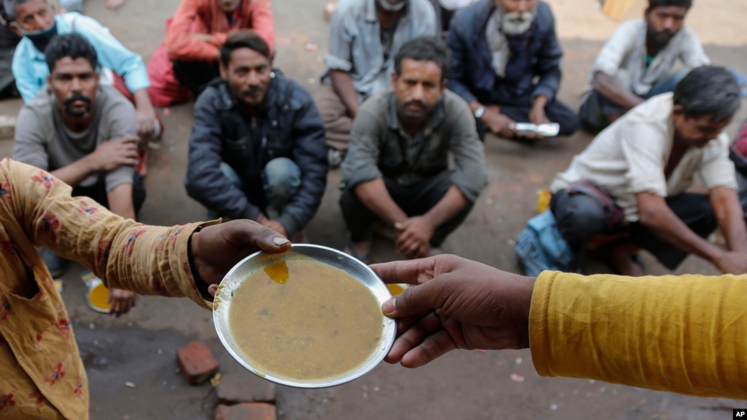 FILE - People wait for free food outside an eatery in Ahmedabad, India, on Jan. 20, 2021.