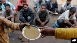 FILE - People wait for free food outside an eatery in Ahmedabad, India, on Jan. 20, 2021.
