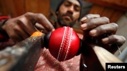 Seorang pekerja menjahit dua bagian kulit dengan inti berbentuk bola di dalamnya untuk membentuk bola kriket di sebuah pabrik di Meerut, 80 kilometer timur laut Delhi, 28 Januari 2011, (REUTERS/Parivartan Sharma)