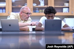 History teacher Matt Brophy, left, works with Flerentin “Flex” Jean-Baptiste, 16, of Medford, Mass., on making up late assignments during summer school at Medford High School, Friday, Aug. 2, 2024, in Medford. (AP Photo/Josh Reynolds)