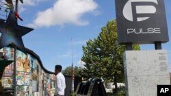 FILE - A survivor of the Pulse nightclub shooting looks at the photos that are a part of the Pulse memorial in Orlando, Florida, Sept. 9, 2022. The 49 victims killed and dozens more survivors of the massacre were remembered Monday with the unveiling of a mural.