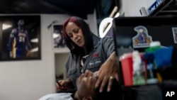 Adelita Valentine, owner of HairFreek Barbers, gives a shave to Cameron Loualhati in Los Angeles, Aug. 21, 2024.