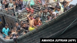 Pengungsi Rohingya yang baru tiba terdampar di perahu karena masyarakat sekitar memutuskan untuk tidak mengizinkan mereka mendarat setelah memberikan air dan makanan di Pineung, Aceh, 16 November 2023. (Foto: AMANDA JUFRIAN/AFP)