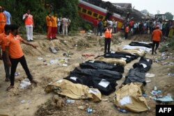 Paramedis dan petugas SAR berdiri di sekitar jenazah korban tabrakan tiga kereta api di dekat Balasore, negara bagian Odisha, India, Sabtu, 3 Juni 2023. (Foto: Dibyangshu Sarkar/AFP)