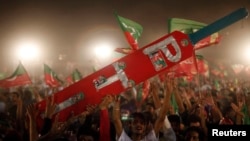 Pendukung Imran Khan, pemain kriket Pakistan yang menjadi politisi dan ketua partai politik Pakistan Tehreek-e-Insaf (PTI) memegang tongkat kriket dalam skala besar selama kampanye pemilu di Lahore, 5 Mei 2013. (Foto: Reuters )