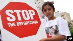 FILE - Khloe Marogi, 8, of West Bloomfield, Mich., wears a T-shirt with her detained father's photo on it at a rally on June 16, 2017, in Detroit. A judge approved a settlement in a lawsuit challenging the detentions.