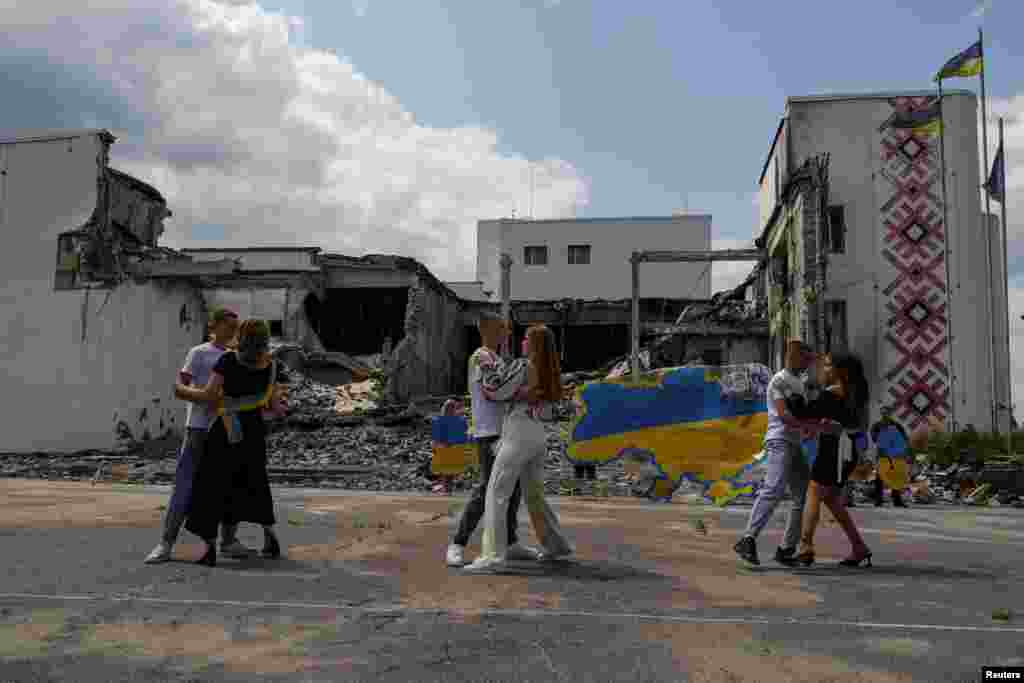 Ученици танцуваат пред локалната Палата на културата уништена од руски воен напад, додека го слават последниот училишен ден во градот Дерхачи, регион Харков, Украина, 17 јуни 2023 година.