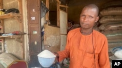 FILE - Isa Ahmed shows the granulated sugar he sells at his shop at a market in Abuja, Nigeria, Oct. 27, 2023. 