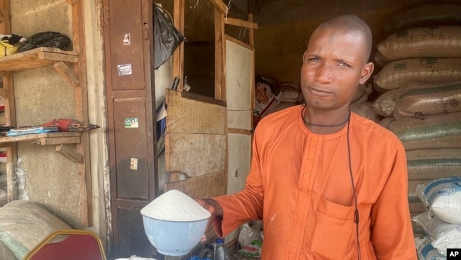 FILE - Isa Ahmed shows the granulated sugar he sells at his shop at a market in Abuja, Nigeria, Oct. 27, 2023.