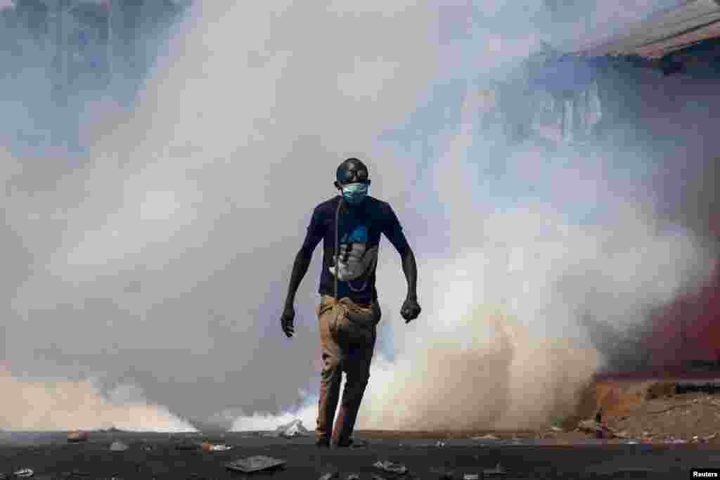 A protester walks amid smoke as supporters of Kenya's opposition leader Raila Odinga of the Azimio La Umoja One Kenya Alliance, demonstrate against the imposition of tax hikes by the government in Nairobi, Kenya.