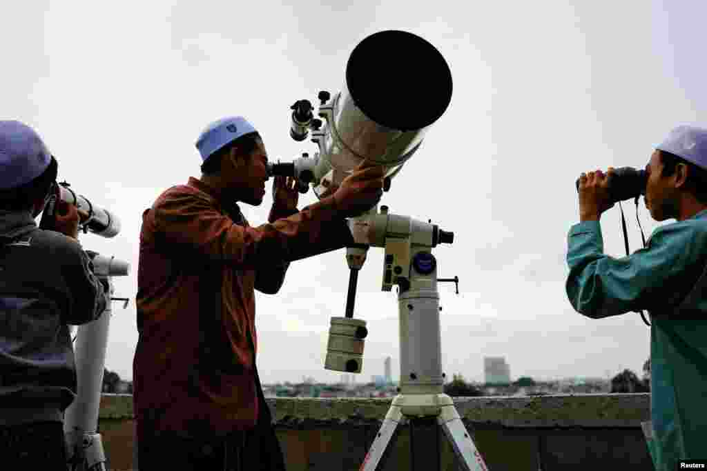 Muslim men look at the position of the moon to mark the first day of the holy fasting month of Ramadan, on the roof of Al-Musyari&#39;in mosque in Jakarta, Indonesia.