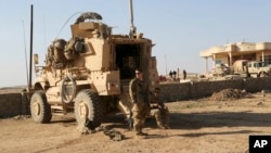 FILE -US Army soldiers stand outside their armored vehicle on a joint base with the Iraqi army, south of Mosul, Feb. 23, 2017. The United States and Iraq have reached an understanding on plans for the withdrawal of US-led coalition forces from Iraq, according to multiple sources