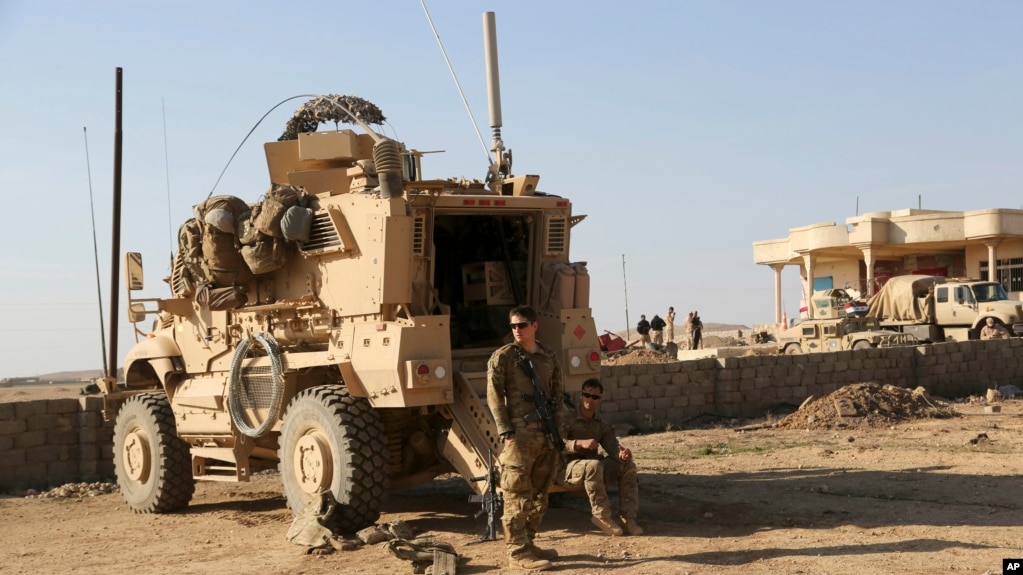 资料照片:在伊拉克摩苏尔以南的一处美伊联合基地,美国陆军士兵站在他们的装甲车辆外。(2017年2月23日)(photo:VOA)