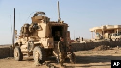 资料照片:在伊拉克摩苏尔以南的一处美伊联合基地,美国陆军士兵站在他们的装甲车辆外。(2017年2月23日)