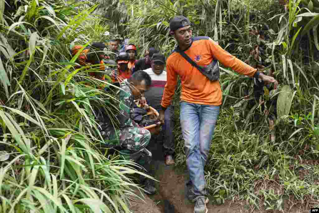 Rescuers carry a victim after the eruption of Mount Marapi in Agam, West Sumatra, Indonesia.