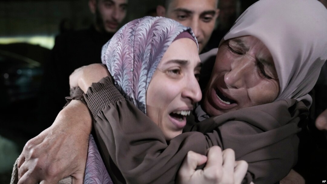 Shuruq Dwayat (kiri), warga Palestina yang ditahan oleh Israel dan akhirnya dibebaskan, dipeluk oleh kerabatnya saat ia tiba di rumahnya di Sur Bahar, Yerusalem timur, pada 26 November 2023. (Foto: AP/Mahmoud Illean)