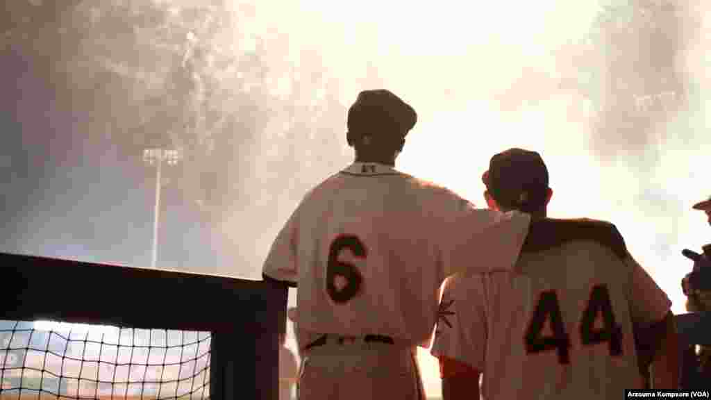 Dennis Kasumba regarde son premier feu d'artifice avec son entraîneur René Rivera à la fin de son deuxième match avec l'équipe de baseball des Frederick Keys au stade Harry Grove à Frederick, Maryland, le 3 juin 2023. (VOA/Arzouma Kompaore)