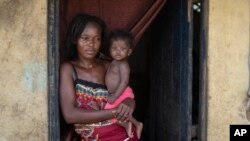 Annie Kopacitino holds her daughter, who she says has been affected by the pollution caused by oil drilling, in her village of Tshiende, Moanda, Democratic Republic of the Congo, Dec. 23, 2023. 