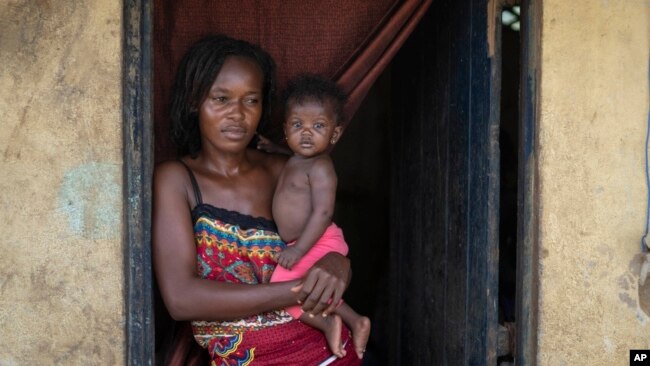 Annie Kopacitino holds her daughter, who she says has been affected by the pollution caused by oil drilling, in her village of Tshiende, Moanda, Democratic Republic of the Congo, Dec. 23, 2023.