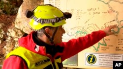 In this photo taken from video, a rescuer inspects the map of Krizna Jama cave near Grahovo, Slovenia, Jan. 7, 2024. 