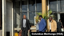 Attorney Alec Muchadehama, black suit, and Tendai Biti, blue suit, leave the Harare court on Feb. 27, 2024. 