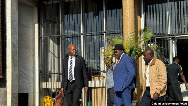 Attorney Alec Muchadehama, black suit, and Tendai Biti, blue suit, leave the Harare court on Feb. 27, 2024.