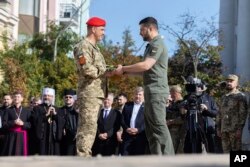 Presiden Ukraina Volodymyr Zelenskyy (kanan) memberikan penghargaan kepada seorang prajurit dalam acara peringatan Hari Kenegaraan di Lapangan Mykhailivska di Kyiv, Jumat 28 Juli 2023.