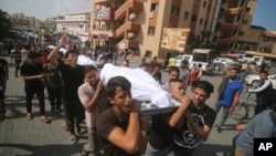 فلسطینی 12 اکتوبر 2023 کو غزہ کی پٹی کےرفاہ میں جنازے کے دوران اسرائیلی گولہ باری میں ہلاک ہونے والے ابو ریاش خاندان کی لاشیں اٹھا رہے ہیں۔فوٹو اے پی