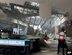 A security guard walks beside the damaged ceiling of a shopping mall in General Santos City, South Cotabato, southern Philippines, Nov. 17, 2023.