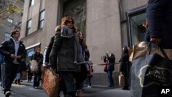 FILE - Shoppers carry bags down Fifth Avenue on Friday, on Nov. 25, 2022, in New York. 