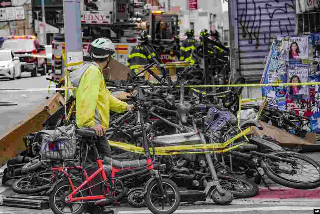 A biker stops to look at a pile of e-bikes in the aftermath of a fire in Chinatown, which authorities say started at an e-bike shop and spread to upper-floor apartments, in New York.