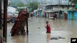 Un hombre camina por una calle inundada después de una fuerte lluvia en Puerto Príncipe, Haití, el sábado 3 de junio de 2023.
