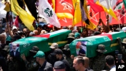 Hamas fighters carry mock coffins of Hamas political chief Ismail Haniyeh and his bodyguard, who were killed in an assassination in Tehran, during a symbolic funeral in Beirut, Lebanon, Aug. 2, 2024.