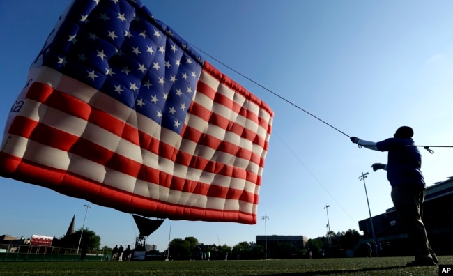 FILE - Wayne Matthew helps raise a hot air balloon shaped like the U.S. flag at Stevens Institute of Technology in Hoboken, N.J. on Tuesday, July 3, 2012. (AP Photo/Julio Cortez)