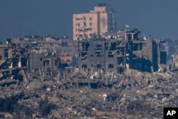 Israeli flags fly atop destroyed buildings in the Gaza Strip, as seen from southern Israel, Nov. 18, 2023.