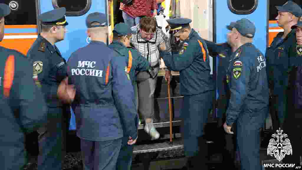 This handout photograph Russian Ermergency Situatoins Ministry personnel assisting people who have been evacuated from the border settlements of the Kursk region as they arrive at a railway station in Oryol. (AFP/HO/Russian Emergency Situations Ministry)