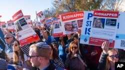 2023年11月14日，参加在华盛顿国家大草坪举行的支持以色列的游行集会的人群挥舞着带有被哈马斯绑架的人质照片的标语。（美联社照片）
