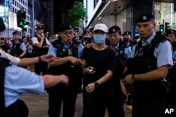 A member of the public is escorted by police after light a smartphone light near Victoria Park, on the 34th anniversary of China's Tiananmen Square crackdown in Hong Kong, June 4 2023.