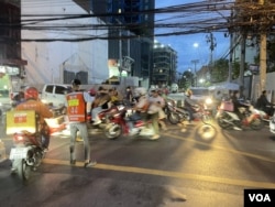 A delivery person, employed by an unlicensed Chinese-owned delivery platform, halts at a red light at Soi Pracharat Bamphen, Huay Khwang district of Bangkok. (Patpon Sabpaitoon/VOA)