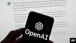 FILE - The OpenAI logo is seen on a mobile phone in front of a computer screen which displays output from ChatGPT, March 21, 2023, in Boston. 