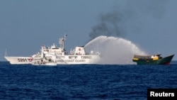 (FILE) Chinese Coast Guard vessels fire water cannons towards a Philippine resupply vessel in the South China Sea, March 5, 2024.