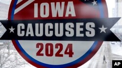 Muškarac hoda preko ulice ispod znaka za Iowa Caucuses u centru Des Moinesa, Iowa, 13. januara 2024.