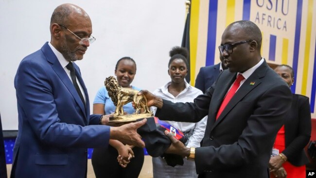 Haitian Prime Minister Ariel Henry, left, is presented a gift by Korir SingOei, Kenya's secretary for foreign affairs, at the United States International University (USIU) in Nairobi, Kenya, March 1, 2024.